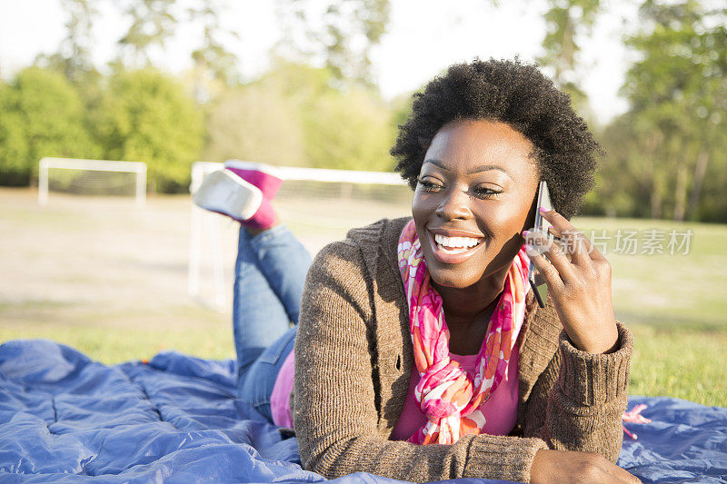 一位非洲裔妇女在公园户外使用手机。