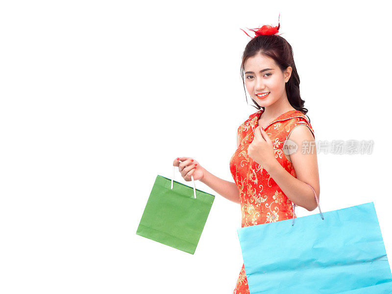 农历新年亚洲女性概念，孤立的亚洲女性穿着红色连衣裙(旗袍)拿着购物袋