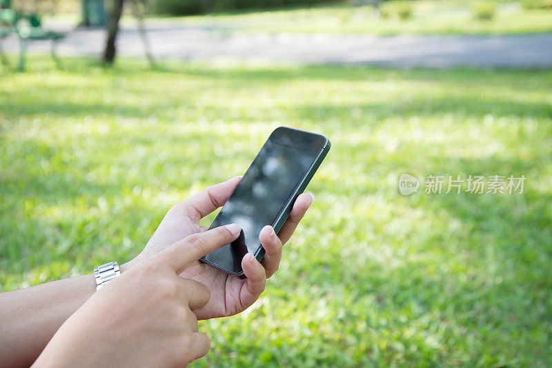 一个女人在城市公园里用手机，特写。