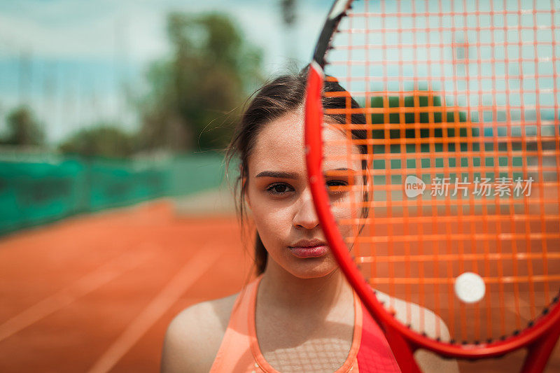 一个强壮的女子网球运动员在户外红土球场上的肖像