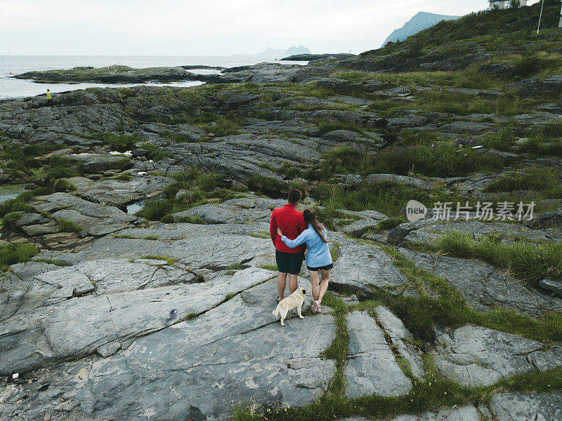 在罗浮敦群岛上，一对夫妇抱着狗看海