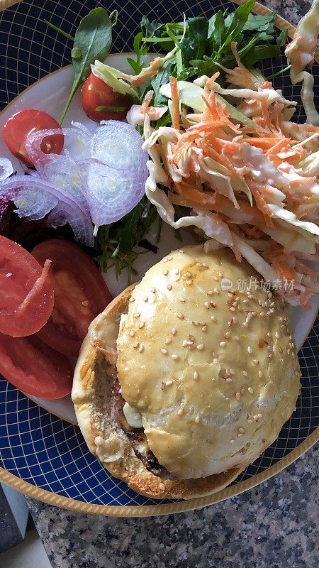 自制凉拌卷心菜、沙拉(番茄、芝麻菜、生菜、红洋葱)和汉堡面包的画面