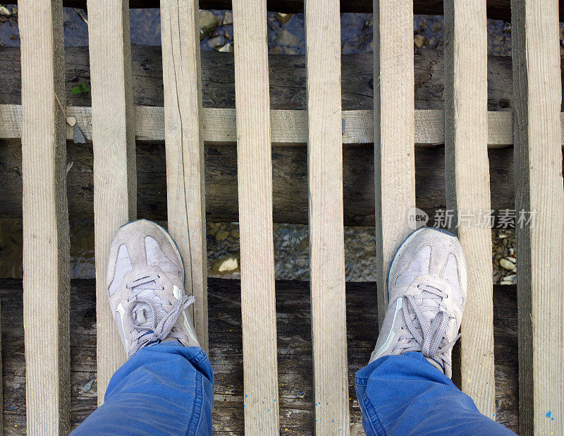 脚踩在桥的木板上。