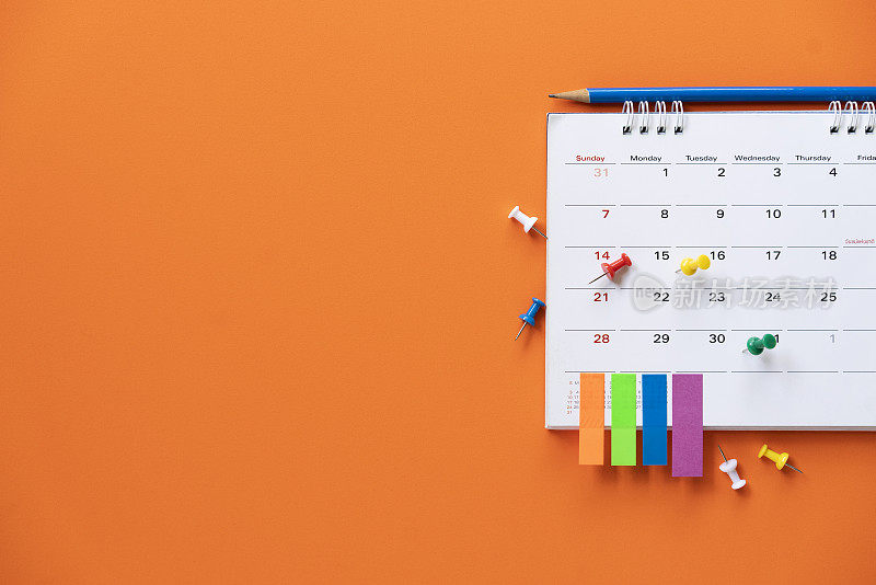 近距离的日历放在橙色的桌子上作为背景，计划商务会议或旅行计划的概念
