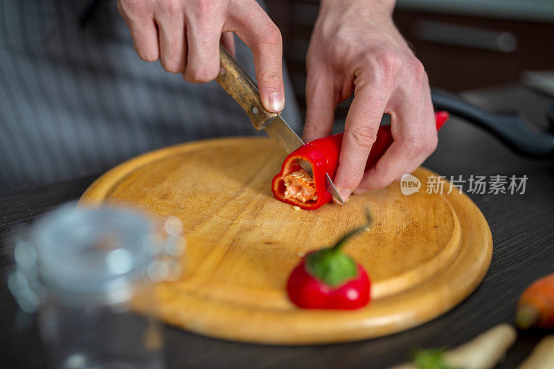 男人在厨房的桌子上切新鲜的春天蔬菜，特写。准备家庭食物，家庭厨房内部。