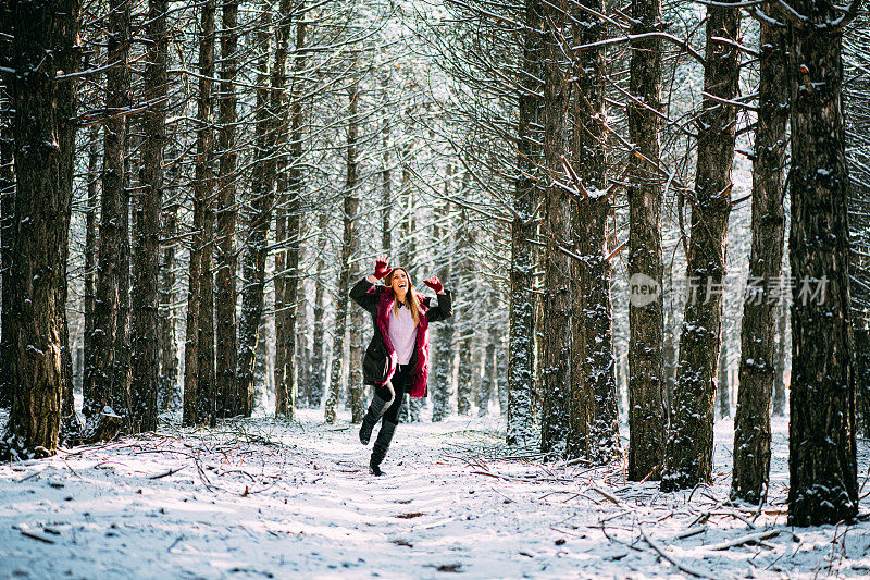 快乐的女人在雪域森林里跳跃