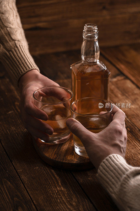 特写的两名男子碰杯威士忌酒饮料一起在酒吧柜台