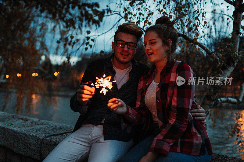 在一个美丽的秋夜，男朋友和女朋友手拿烟花