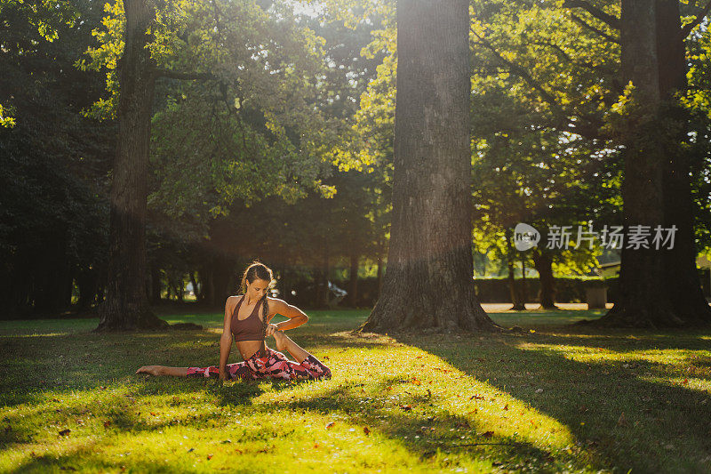 年轻女子在公园的草坪上做瑜伽