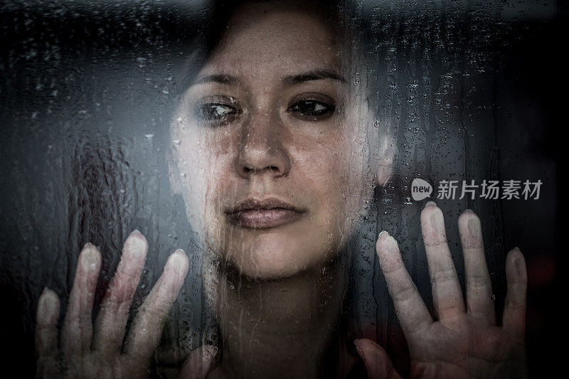 沮丧的女人望着下雨的窗外