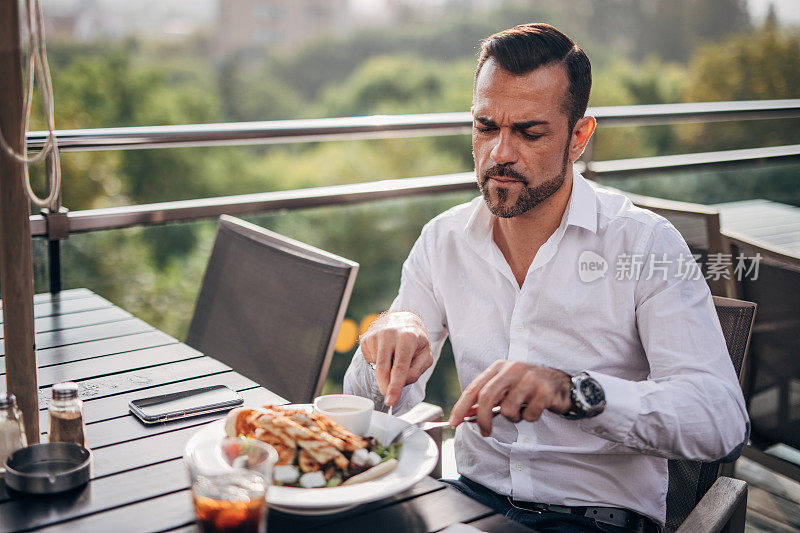 英俊成熟的商人在餐厅露台上享受美食