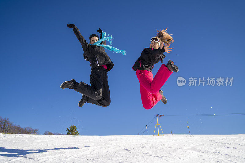 年轻的滑雪者在雪山上嬉戏跳跃