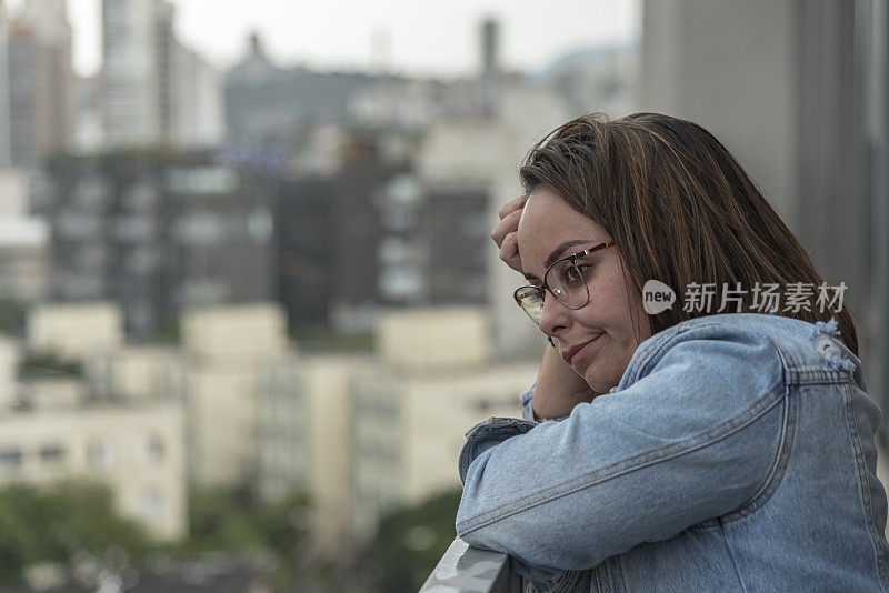 阳台上的年轻女子看起来很沮丧