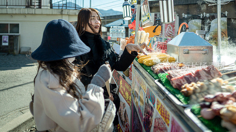 两名年轻美丽的女游客购买当地街头小吃的镜头