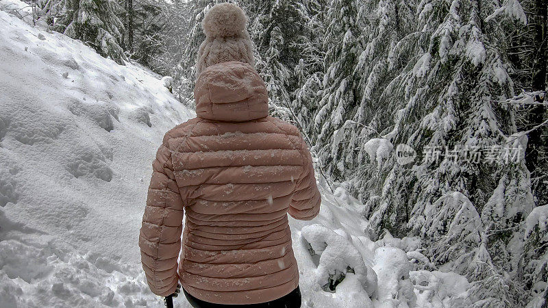 女性徒步旅行者沿着雪道行走