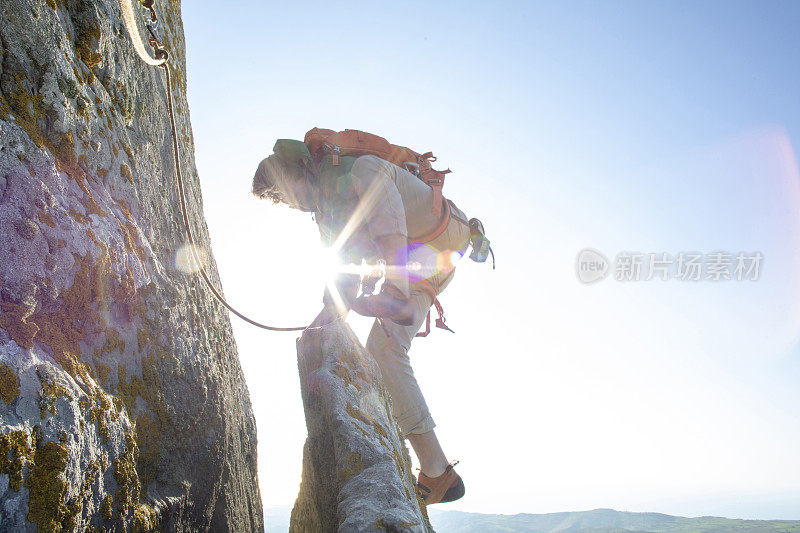 登山者在日出时攀登岩面