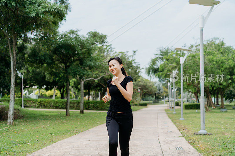 快乐的年轻亚洲女人在早上在公园跑步