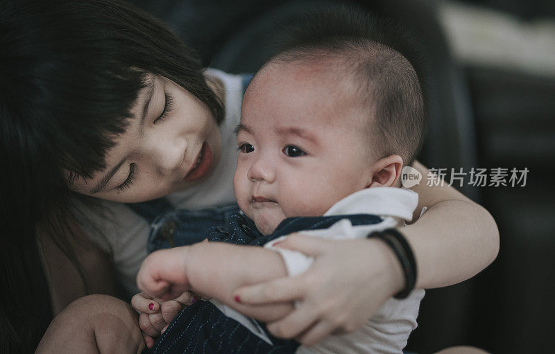 一个亚裔中国小妹妹照顾着，说话，抱着她正在哭的小弟弟