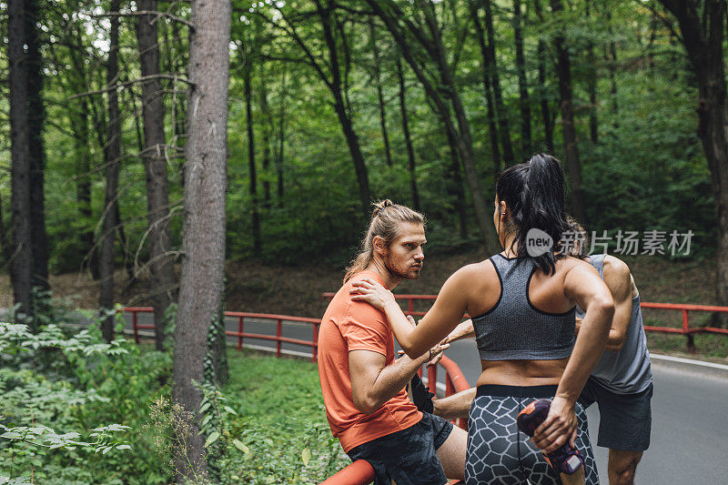 跑步伙伴:三个跑步者组成的团队在大自然中一起锻炼后进行伸展运动