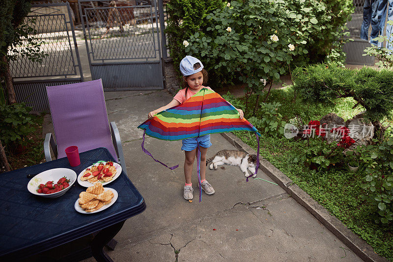 吃完早餐后，小女孩兴奋地玩着彩虹风筝玩具