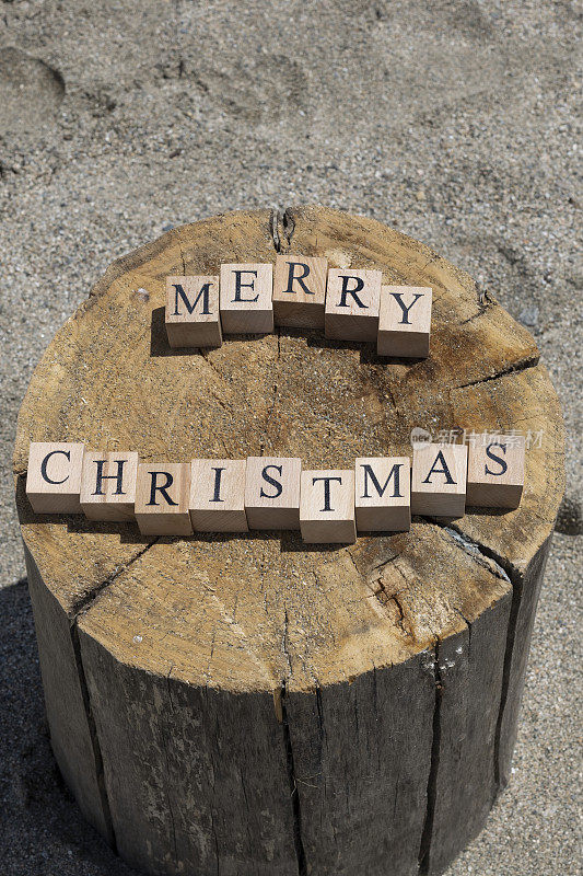 圣诞快乐，木头方块上的文字。小方块在树桩上。