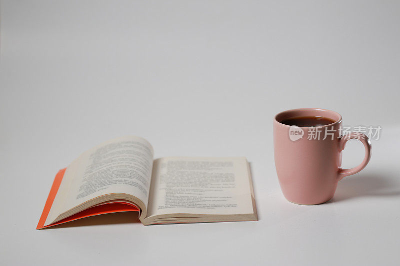 书和粉红色的咖啡杯在白色孤立的背景