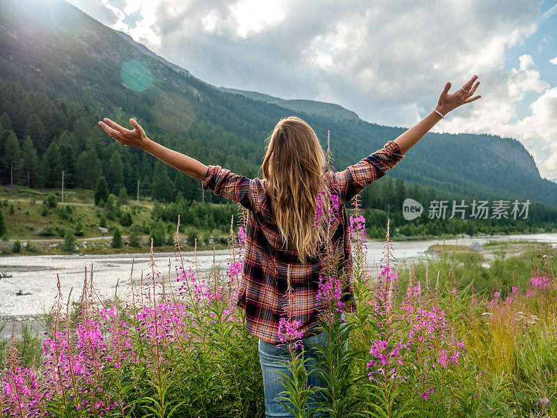 日出时，河边的野花场上，欢呼的妇女张开双臂