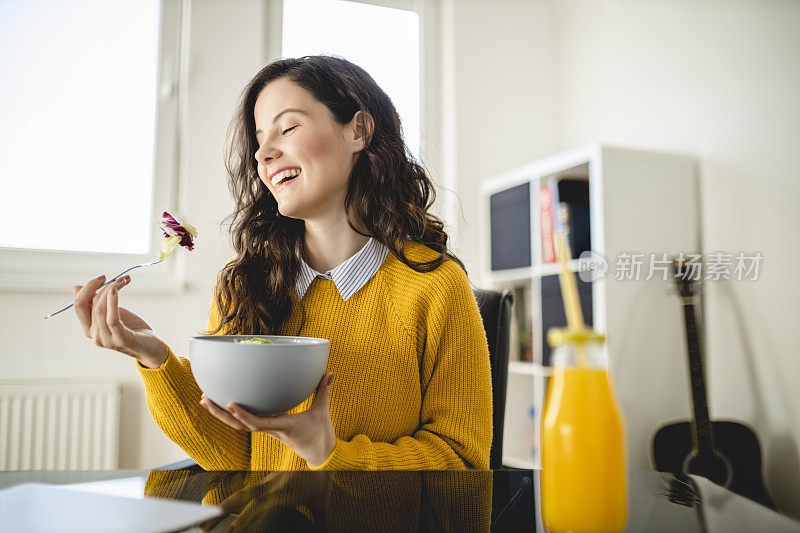 年轻女子一边吃沙拉和喝橙汁一边参加网上研讨会