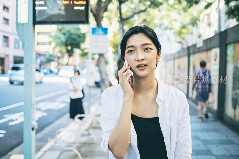 一名亚洲女性在城市街道上使用智能手机