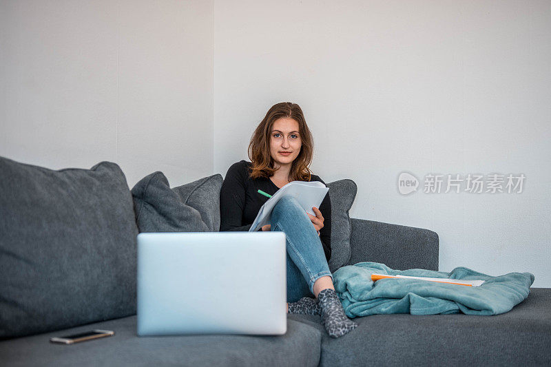 白人妇女用笔记本电脑做笔记和听在线讲座