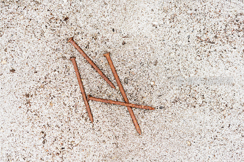 锈迹斑斑的铁钉躺在沙滩上，让人想起耶稣受难