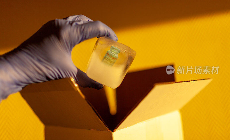 特写手和手术手套从低温储存的COVID-19疫苗内的盒子中取出冰块。标记SARS-CoV-2对抗冠状病毒
