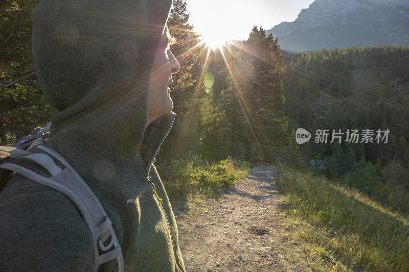 成熟的徒步旅行者穿着连帽衫看日出的山