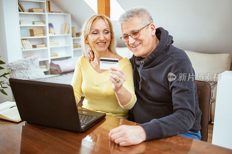 一对成熟的快乐夫妇用笔记本电脑在网上购物