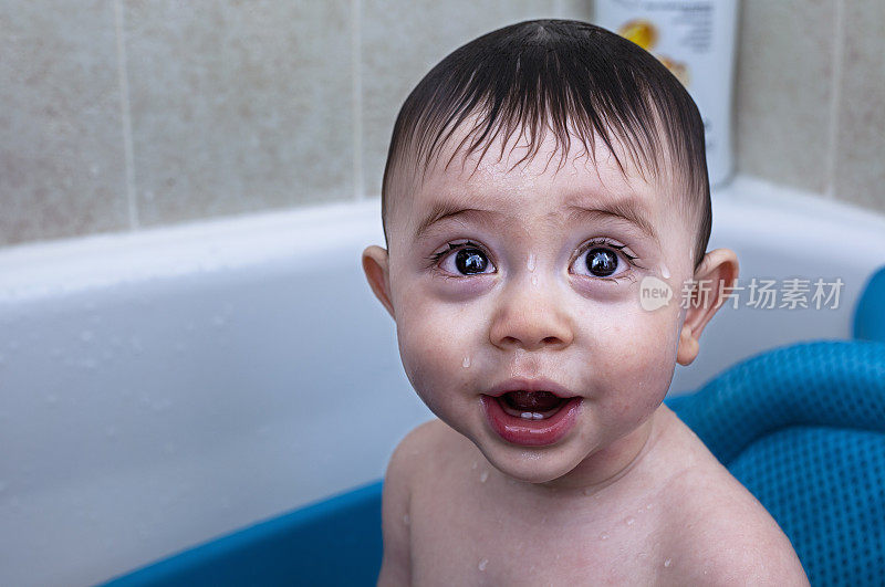 可爱的混血亚裔白种人婴儿男孩与大棕色眼睛在浴缸微笑