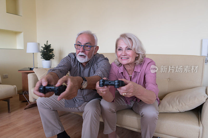 英俊的老男人和他的老妻子在玩游戏机，同时花时间在家里。