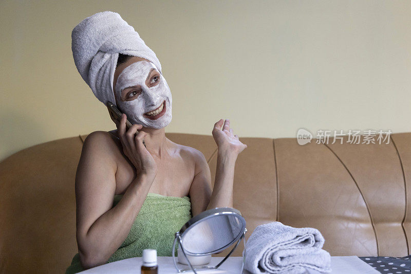 在家做水疗。一位戴着美容面具的年轻女子正在讲电话。虚拟温泉的一天。