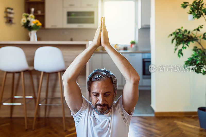 英俊成熟的男人在家里练习禅宗瑜伽
