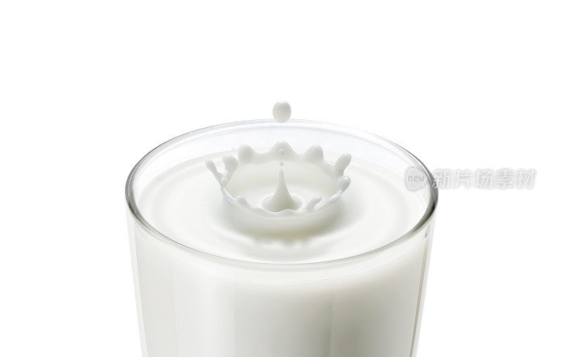 牛奶滴在玻璃上的特写产生波纹和皇冠形状的飞溅，展示新鲜牛奶，健康食品，早餐饮料的概念。在牛奶杯中滴入牛奶，产生皇冠状的波浪和飞溅。
