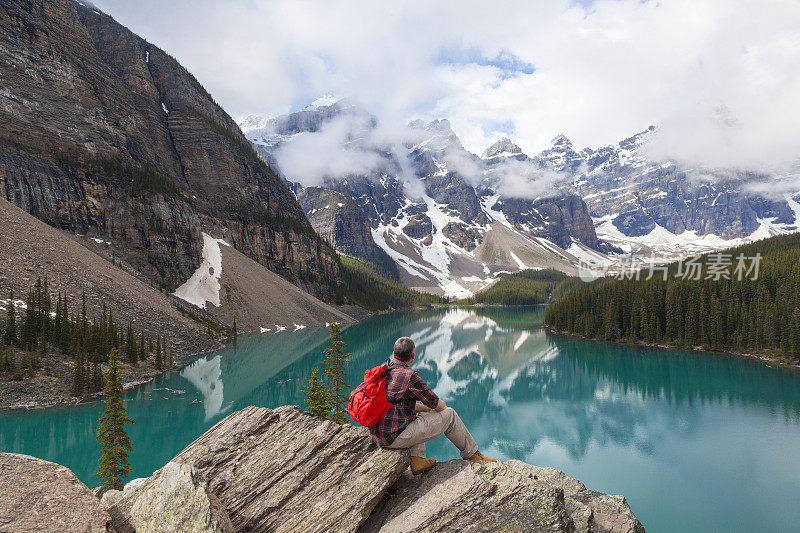 一个男人站在岩石上看冰碛湖的美丽照片