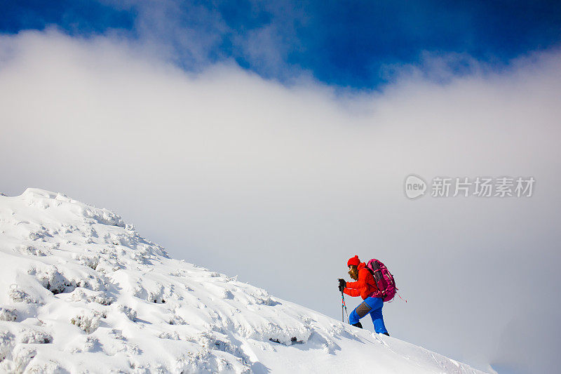 背包登山者在雪坡上行走。