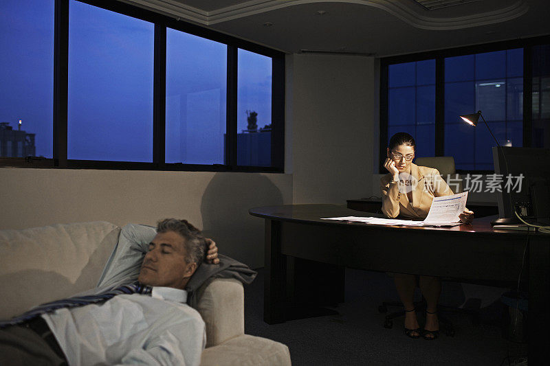 女商人工作到很晚，男人睡在办公室沙发上