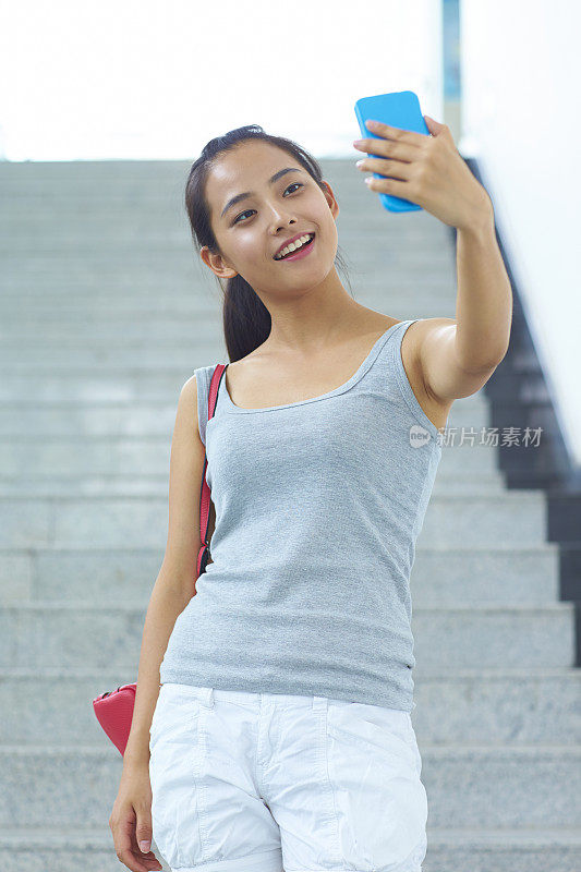 年轻的亚洲大学生用手机讲她的照片