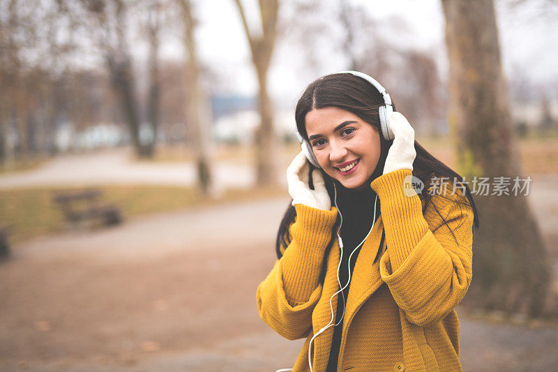 一个女人在当地的公园里戴着耳机听音乐