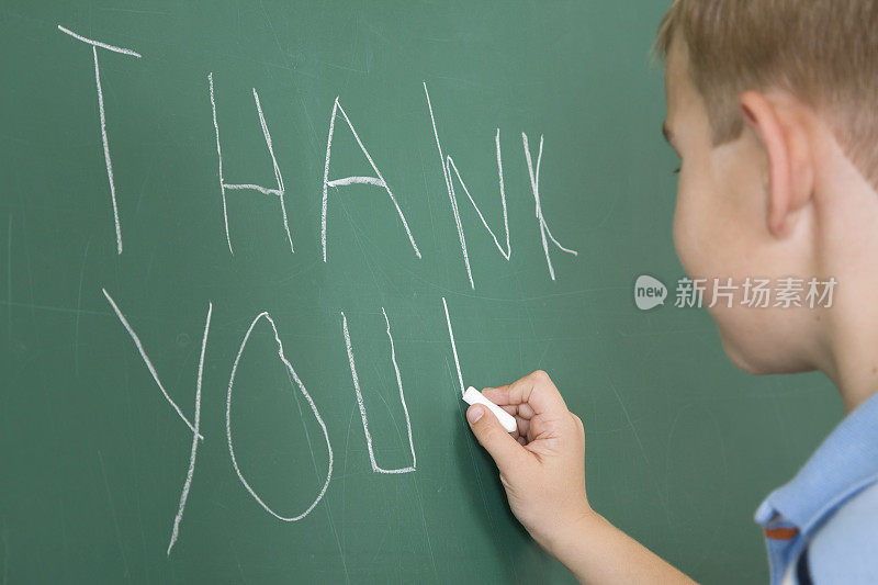 年轻的学生在学校黑板上写“谢谢你”