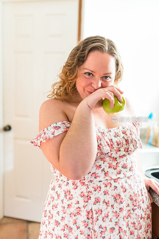 胖女人在厨房里吃苹果