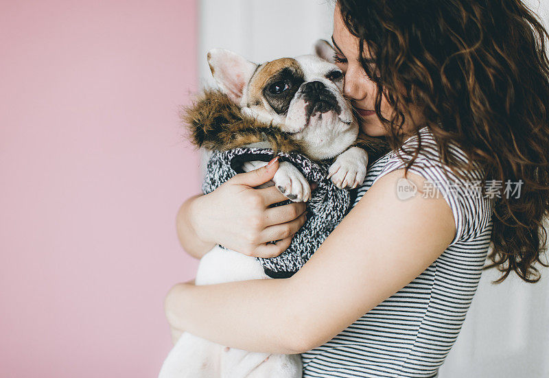 一个自信的女人抱着一只法国斗牛犬