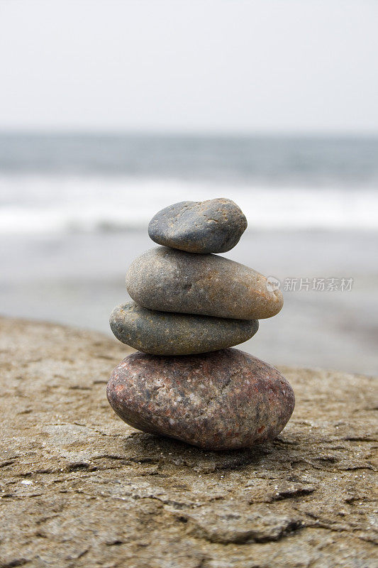四块平衡的石头放在岩石海滩上