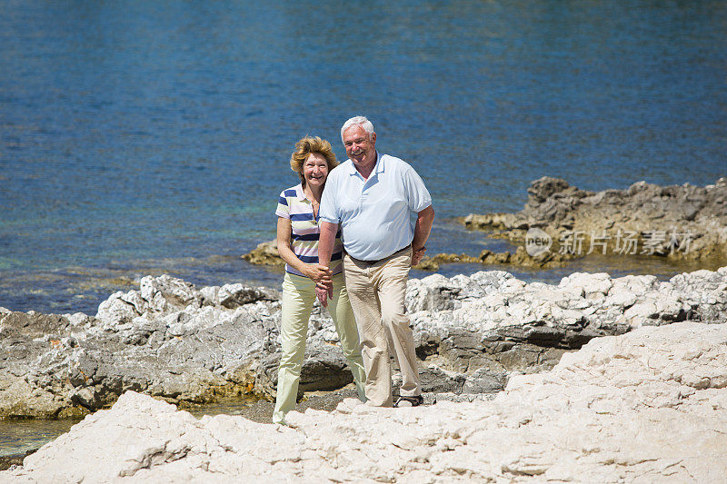 老年情侣微笑着站在沙滩上度假