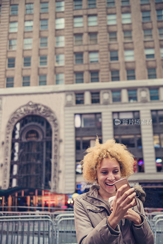 混血女子在城市街道上用手机发短信。
